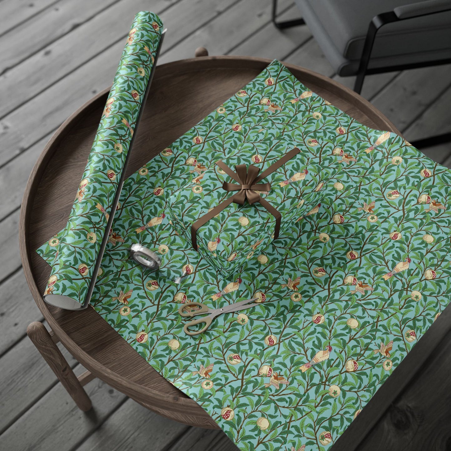 Green floral-patterned wrapping paper with a bow and scissors on a wooden surface.