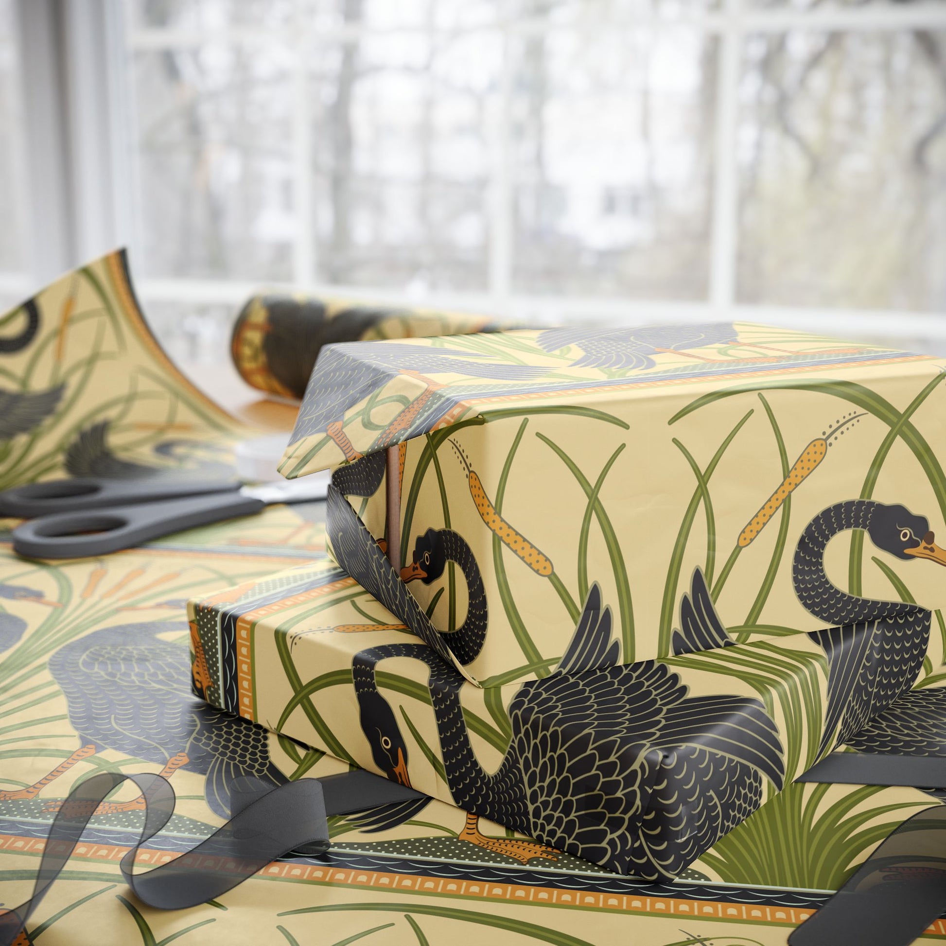 Gift box with black swan design on patterned paper, scissors visible.