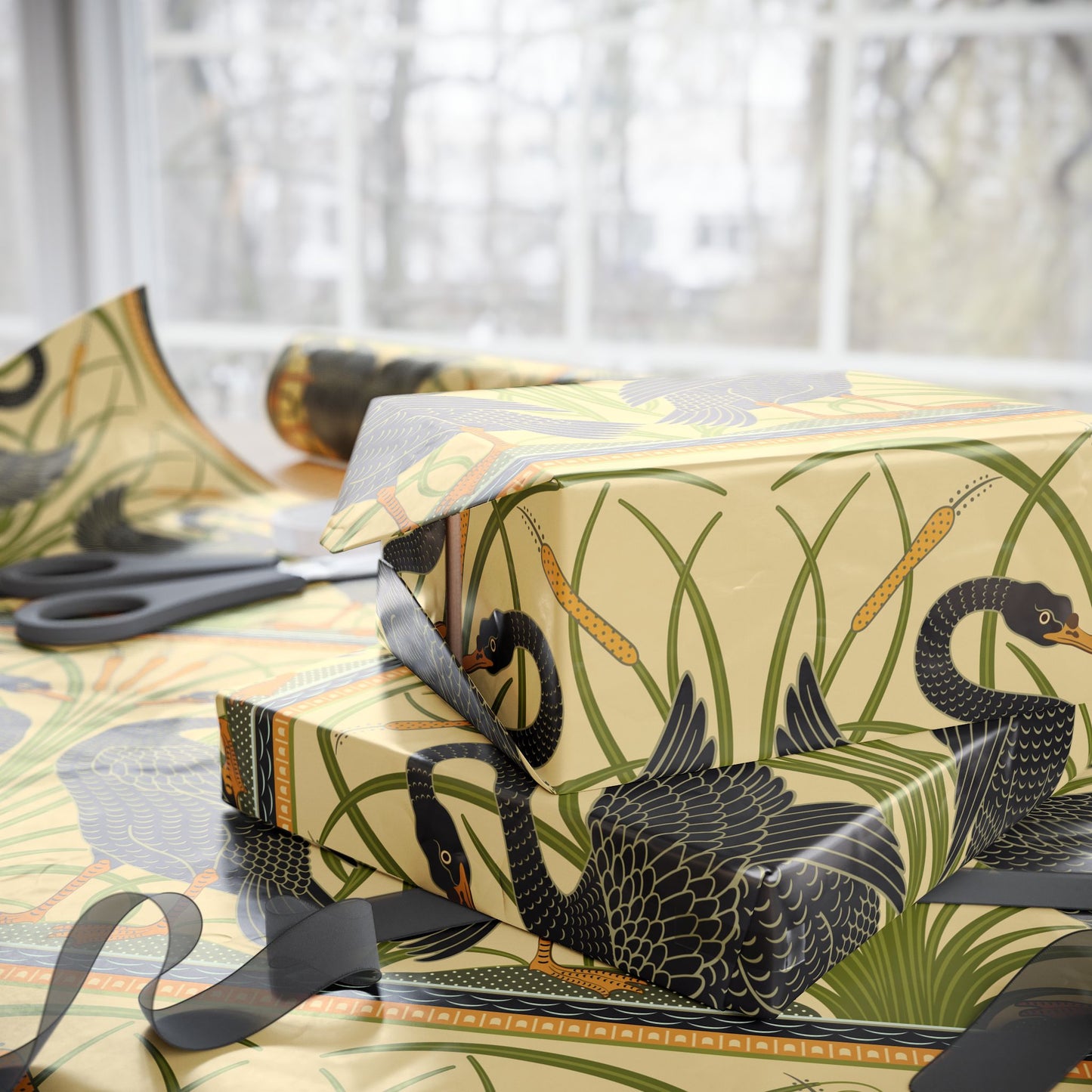 Gift box with black swan design wrapped in decorative paper with scissors on a light background