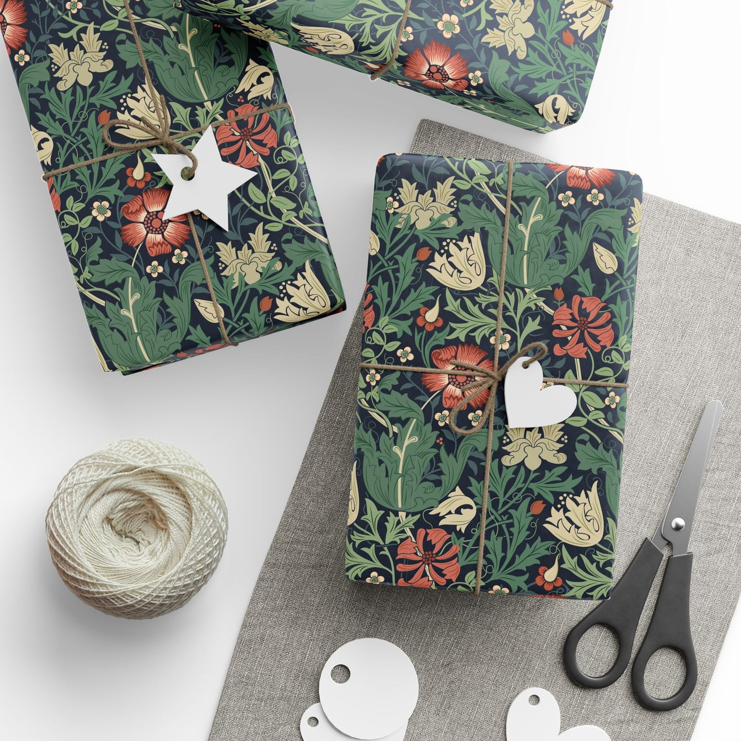 Floral-patterned gift wrap with decorative tags and scissors on a white surface