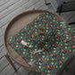 Floral-patterned mat on a wooden tray with a spider decoration on a wooden floor.