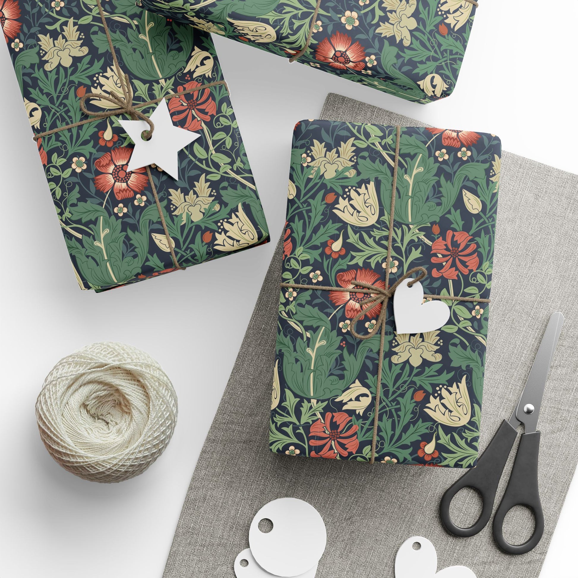 Gift wrap with floral pattern, scissors, and yarn on a white surface