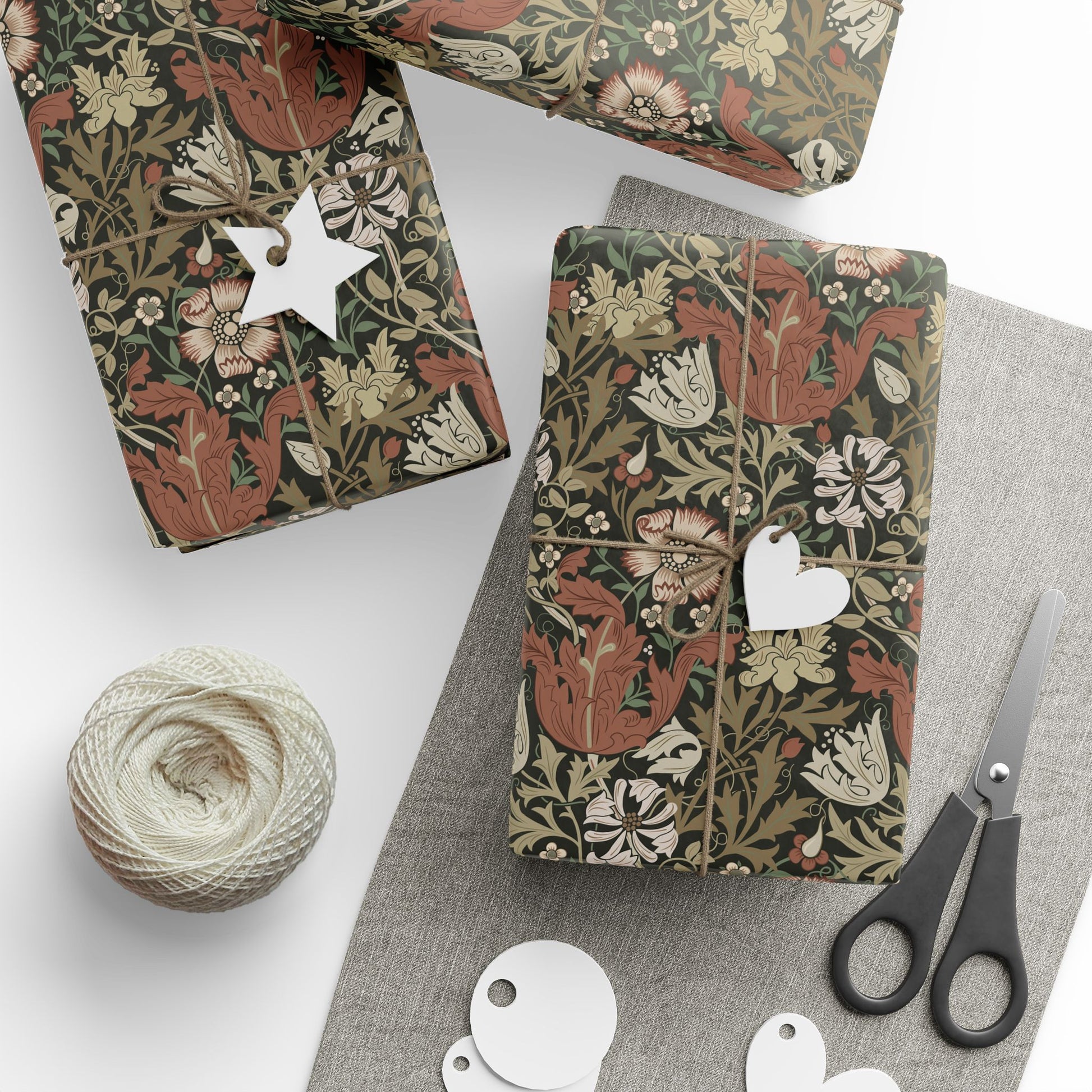 Gift boxes with floral patterns, tags, yarn, and scissors on a white surface