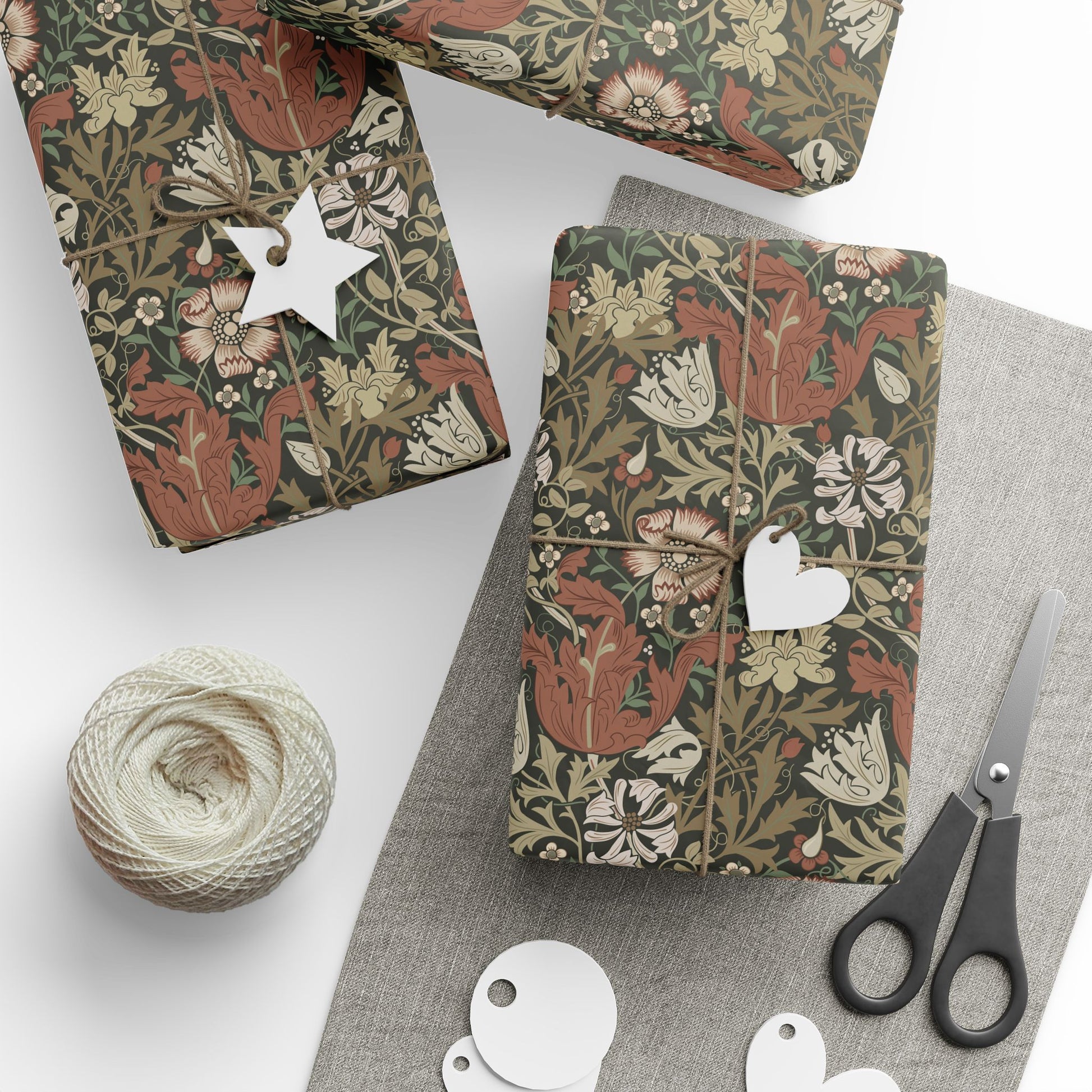 Gift boxes wrapped in floral paper with decorative tags and scissors on a white surface