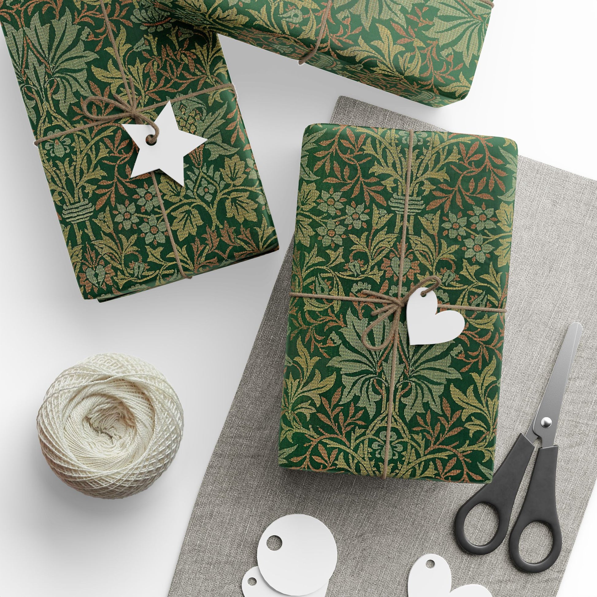 Green patterned gift wrap with decorative tags and scissors on a white surface
