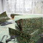 Gift box wrapped in green floral paper with scissors on a table.