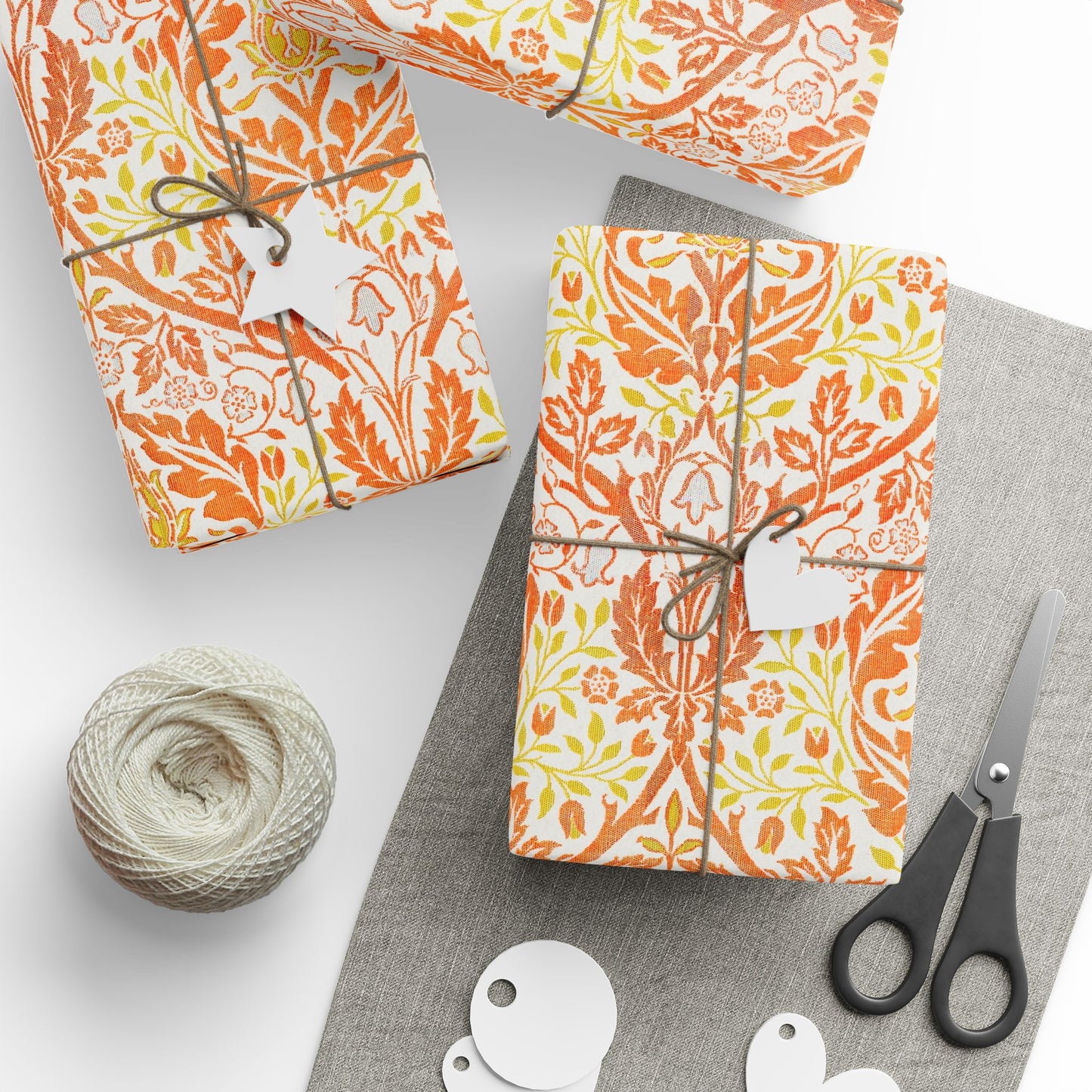 Gift-wrapped items with floral pattern, scissors, and yarn on a white surface
