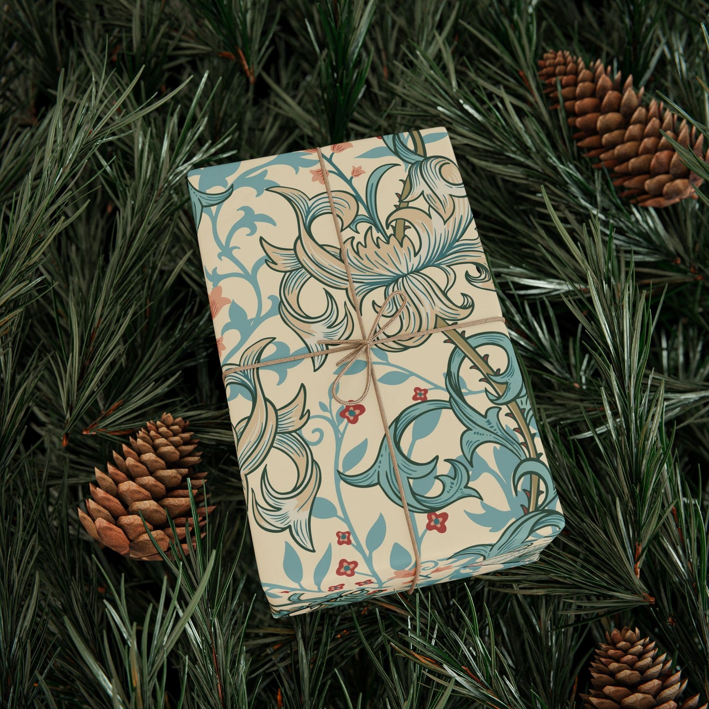 Gift box with decorative paper on a bed of pine needles and pine cones