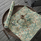 Floral-patterned gift wrap with a brown ribbon on a wooden surface