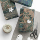 Gift boxes wrapped in nature-themed paper with decorative tags and scissors on a white surface.