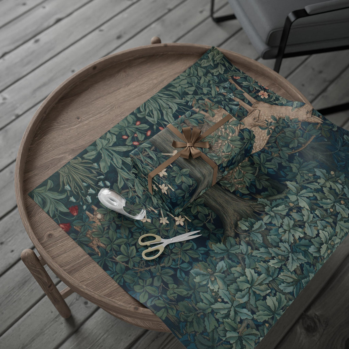 Gift wrapped in green floral paper with a brown ribbon on a wooden tray.