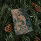 Folded fabric with nature-themed design on a bed of pine needles and pine cones