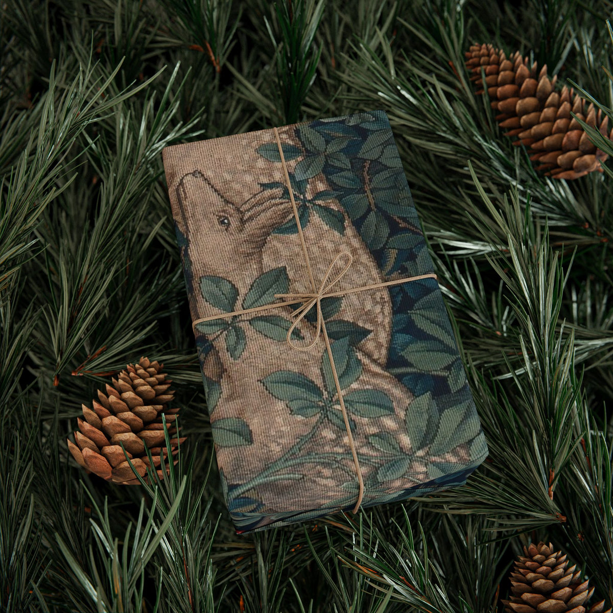 Folded fabric with nature-themed design on a bed of pine needles and pine cones