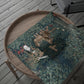 Wooden tray with a green floral-patterned wrapping paper, fabric, scissors, and a spool of thread on a wooden surface.