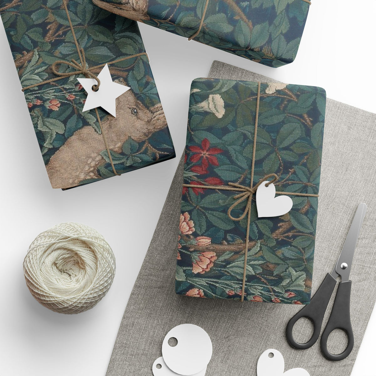 Gift boxes wrapped in floral paper with decorative tags and scissors on a white surface