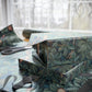 Two wrapped presents with leaf pattern on a table with scissors in the background.