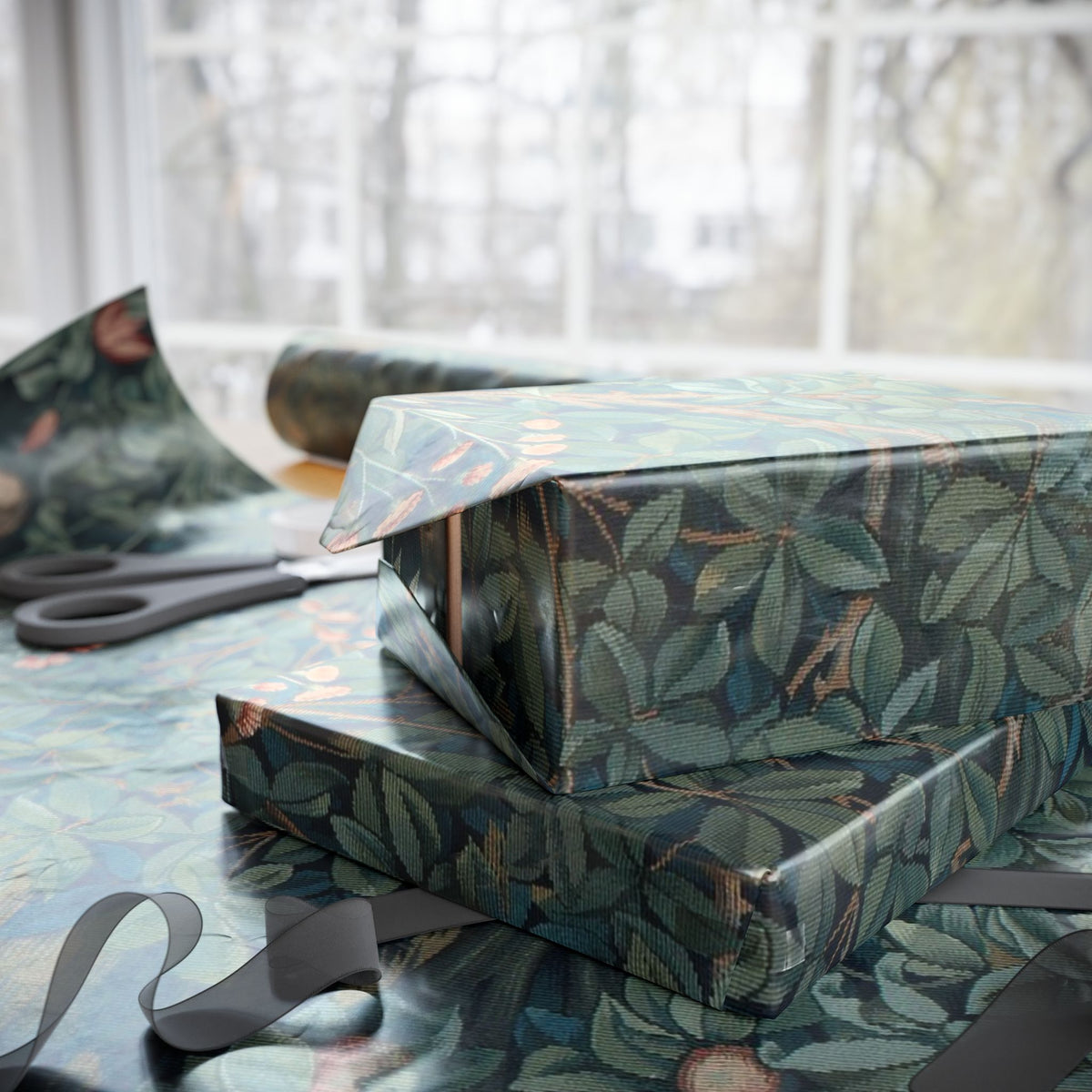 Two wrapped presents with leaf pattern on a table with scissors in the background.