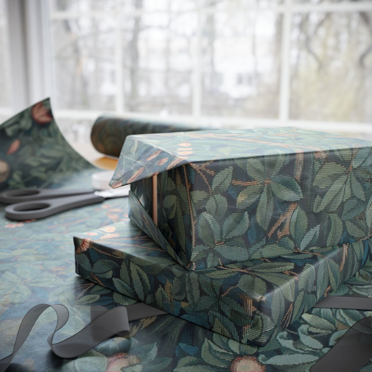Stack of wrapped presents with green leaf pattern on a table with scissors and additional wrapping paper.