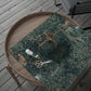 Wooden tray with a green floral patterned cloth, scissors, and a spool of thread on a wooden surface.