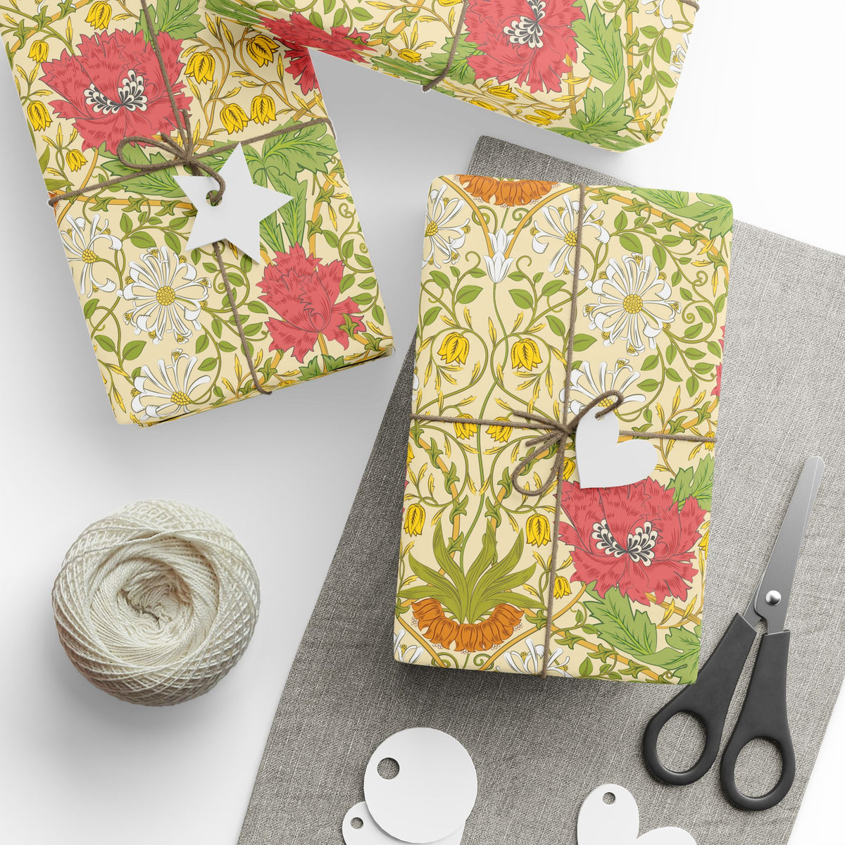 Gift-wrapped packages with floral patterns, scissors, and yarn on a white surface