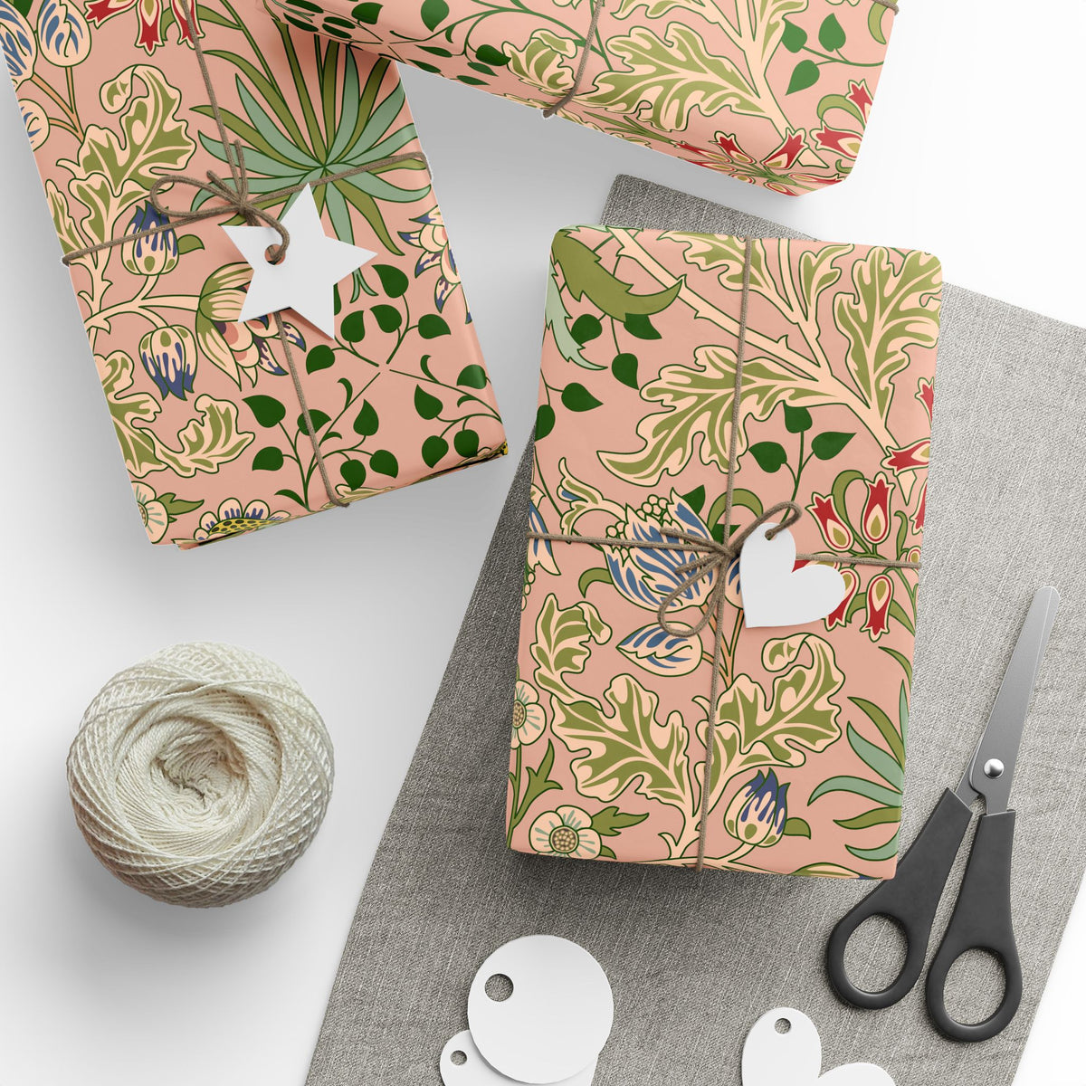 Gift boxes wrapped in pink floral paper with scissors and yarn on a gray surface