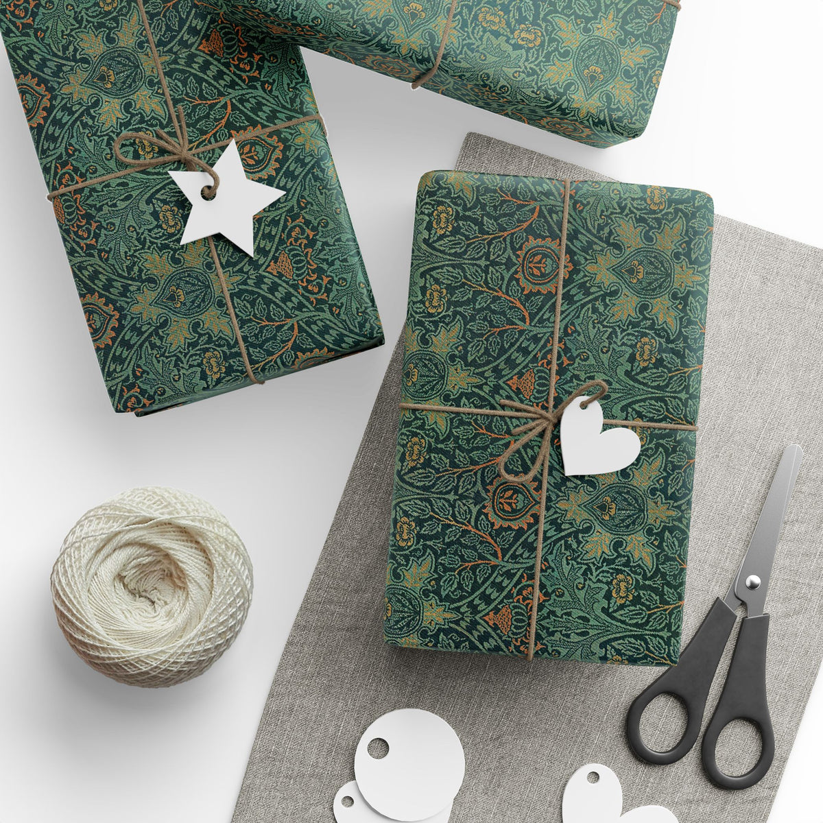 Green patterned gift wrap with decorative tags and scissors on a white surface