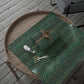 Green patterned fabric with a roll of tape, scissors, and a decorative bow on a wooden surface.
