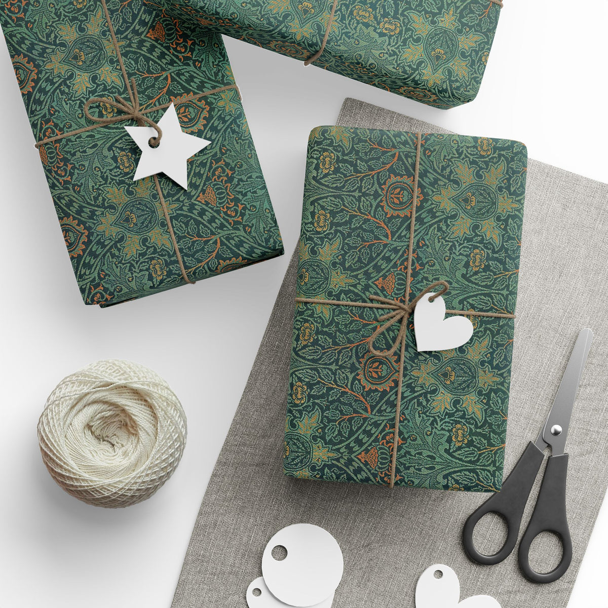Decorative green packages with paper tags and scissors on a white surface