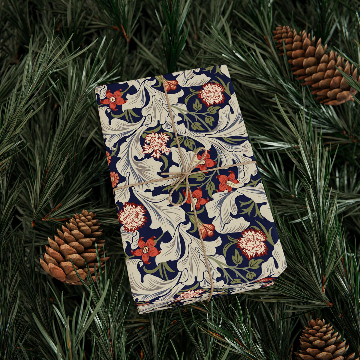 Floral-patterned notebook on green leaves with pine cones