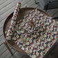 Floral-patterned wrapping paper on a wooden surface with a chair in the background