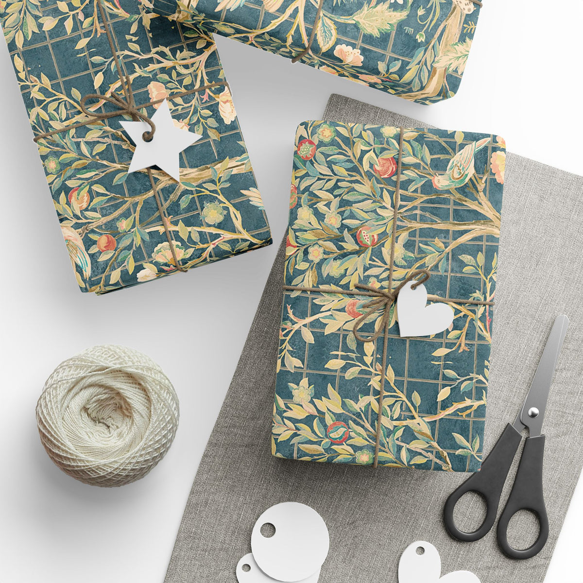 Gift boxes wrapped in decorative paper with a pair of scissors and yarn on a white surface
