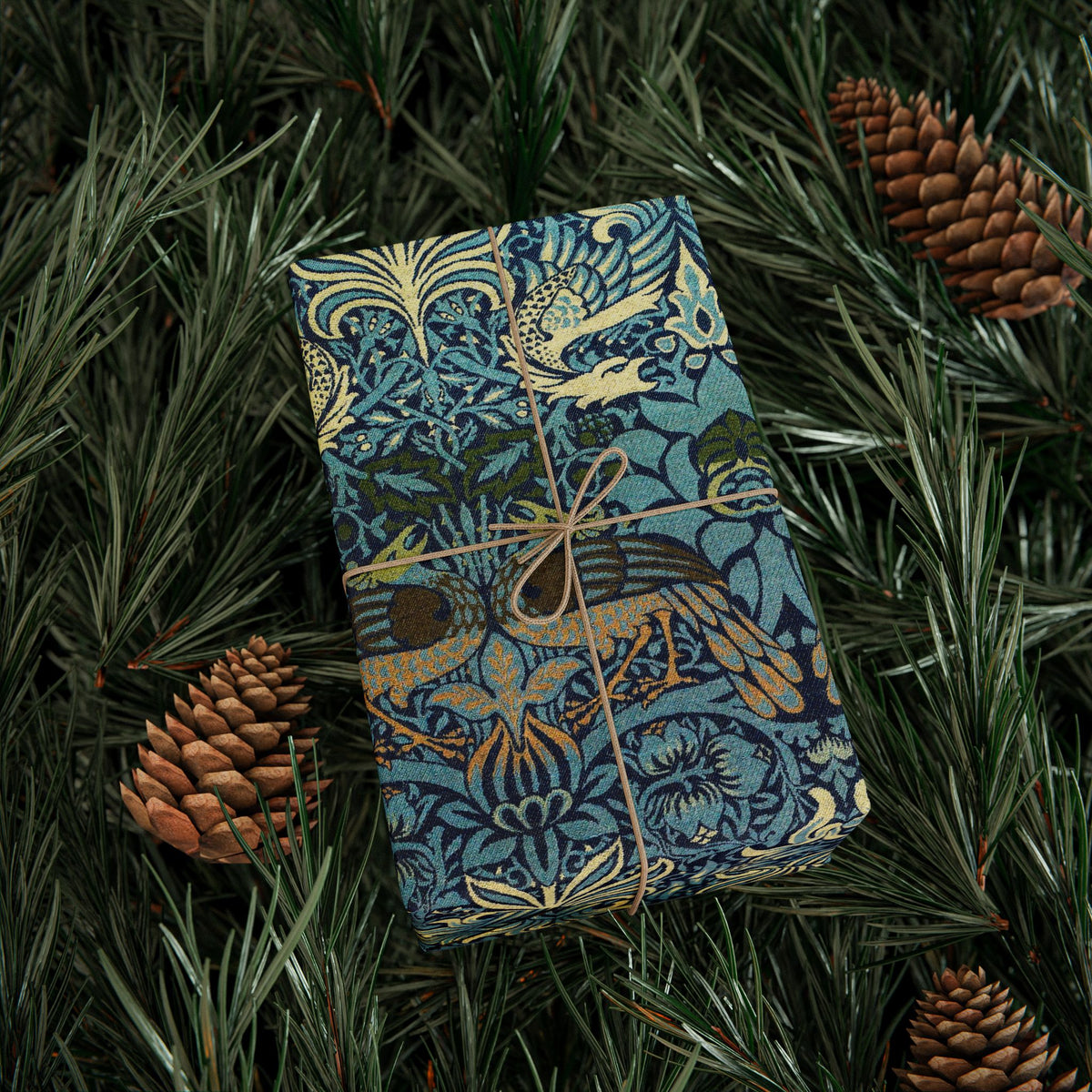 Decorative box with intricate patterns on a bed of pine needles and pine cones