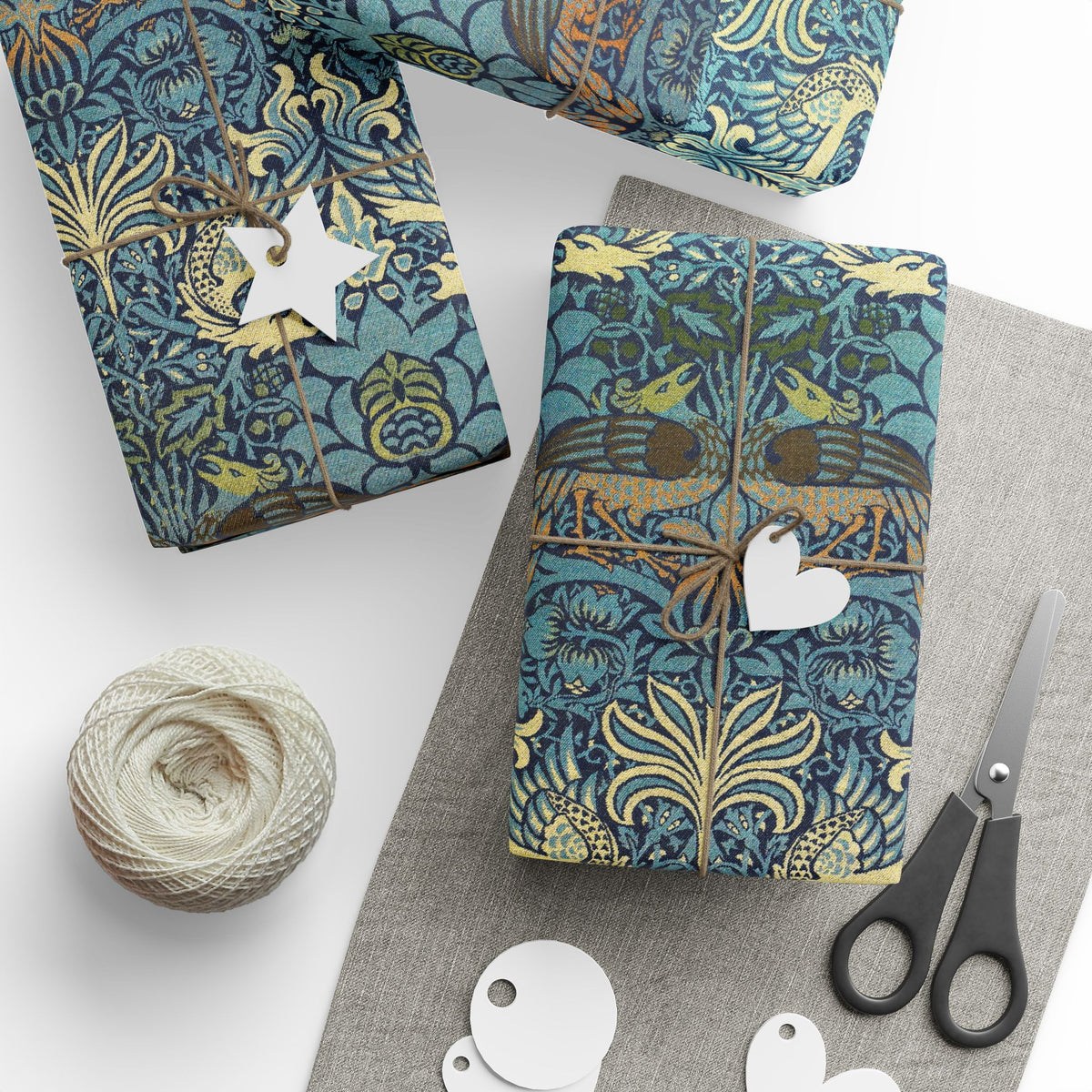 Gift-wrapped items with decorative paper, scissors, and yarn on a white surface