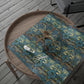 Patterned fabric on a wooden tray with scissors on a wooden floor.