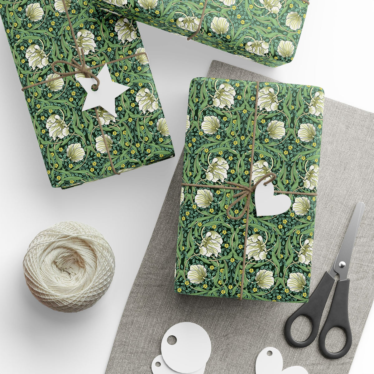 Gift-wrapped packages with floral patterns on a white surface with scissors and yarn.
