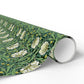 Roll of floral wrapping paper with green leaves and white flowers on a white background
