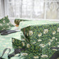 Green floral-patterned box with ribbon on a matching fabric background