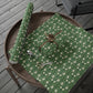 Green floral-patterned fabric with a pair of scissors on a wooden surface