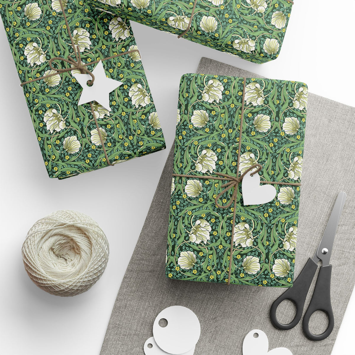Green floral-patterned gift wrap with decorative elements on a white surface.