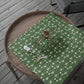 Green floral-patterned tablecloth on a wooden tray with a wooden chair in the background.