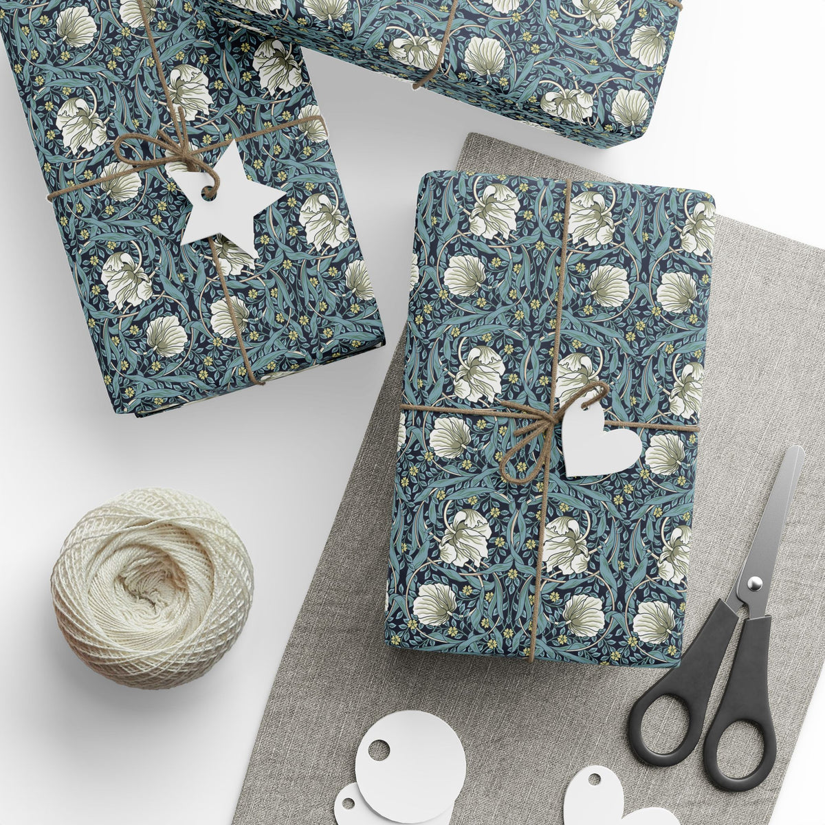 Gift wrap with floral pattern, star-shaped tag, heart-shaped tag, and scissors on a white surface.