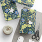 Gift-wrapped items with floral pattern, scissors, and yarn on a white surface