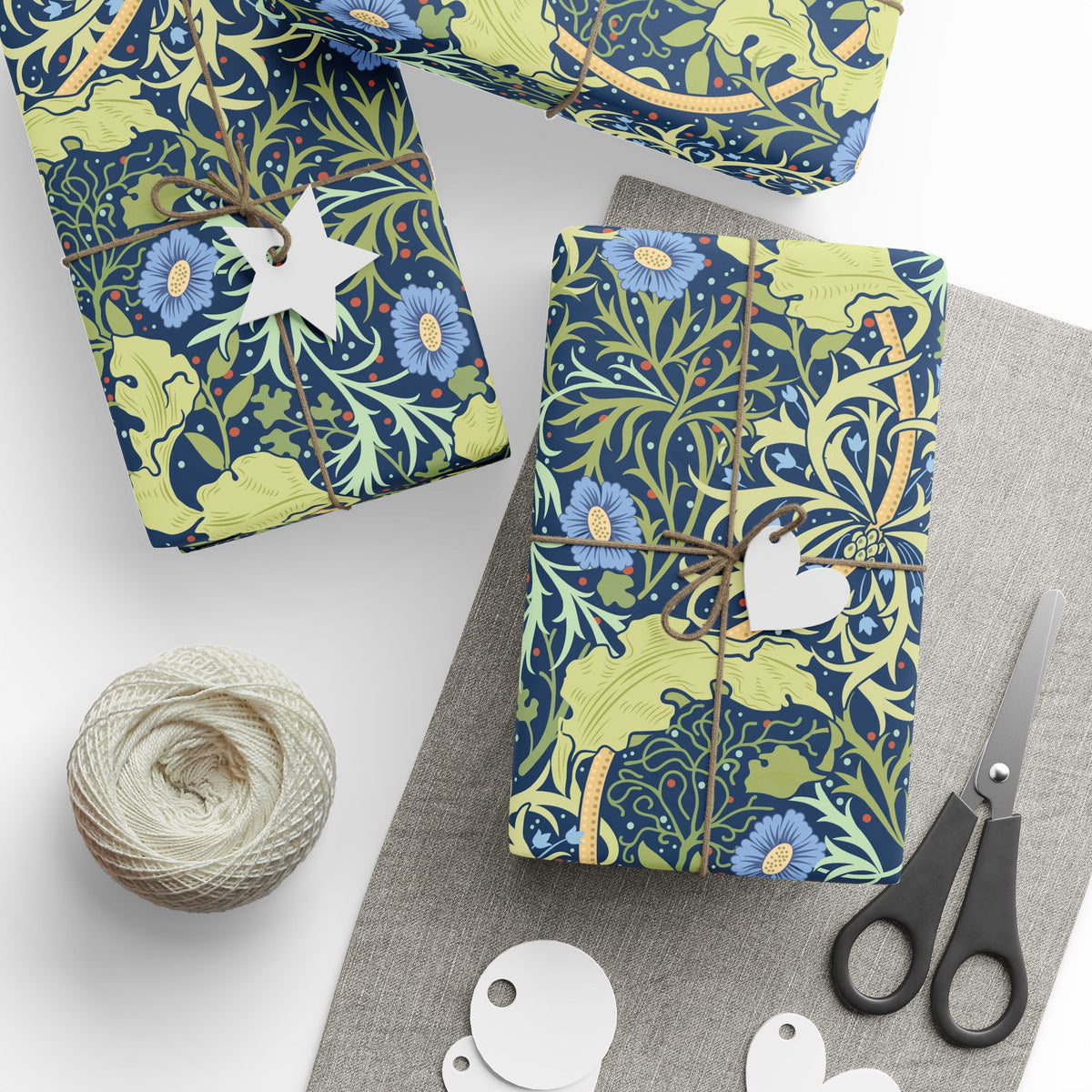 Gift-wrapped items with floral patterns, scissors, and twine on a white surface