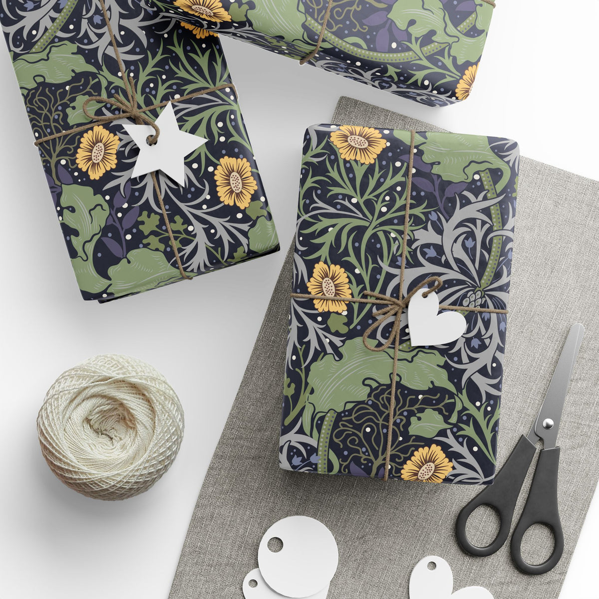 Gift-wrapped packages with decorative paper, scissors, and yarn on a white surface