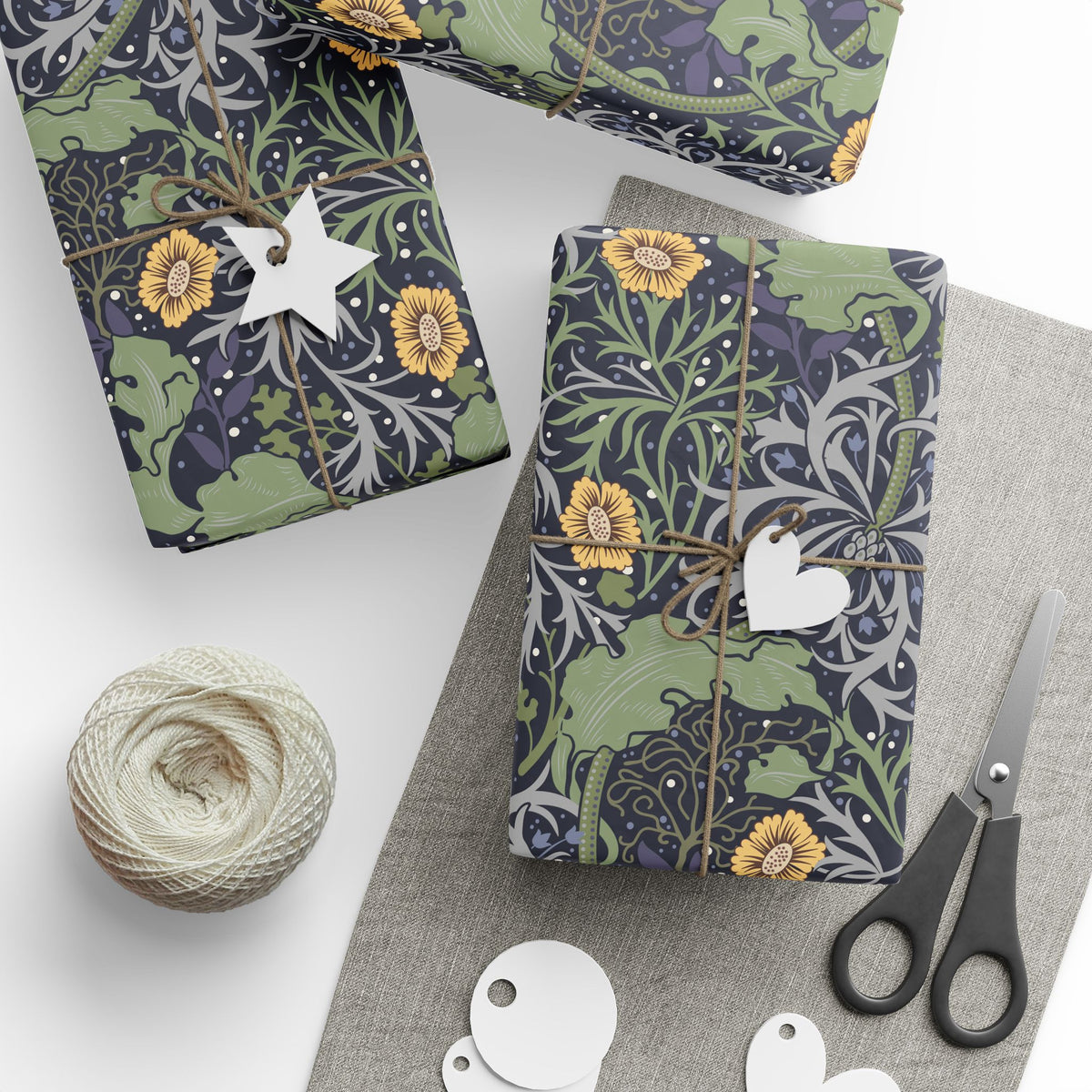 Gift-wrapped packages with floral patterns, scissors, and yarn on a white surface