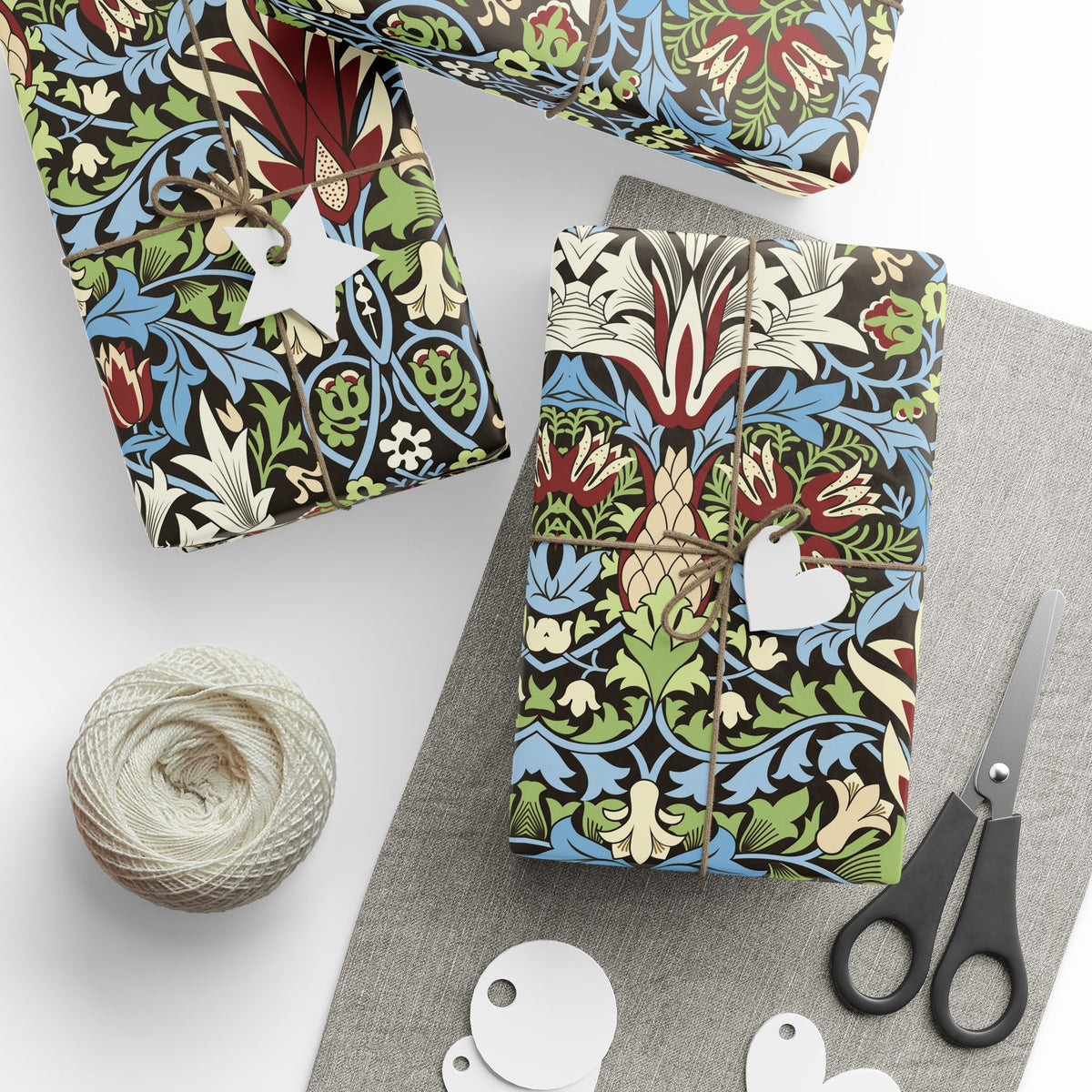 Colorful patterned gift boxes with a ball of yarn and scissors on a white surface