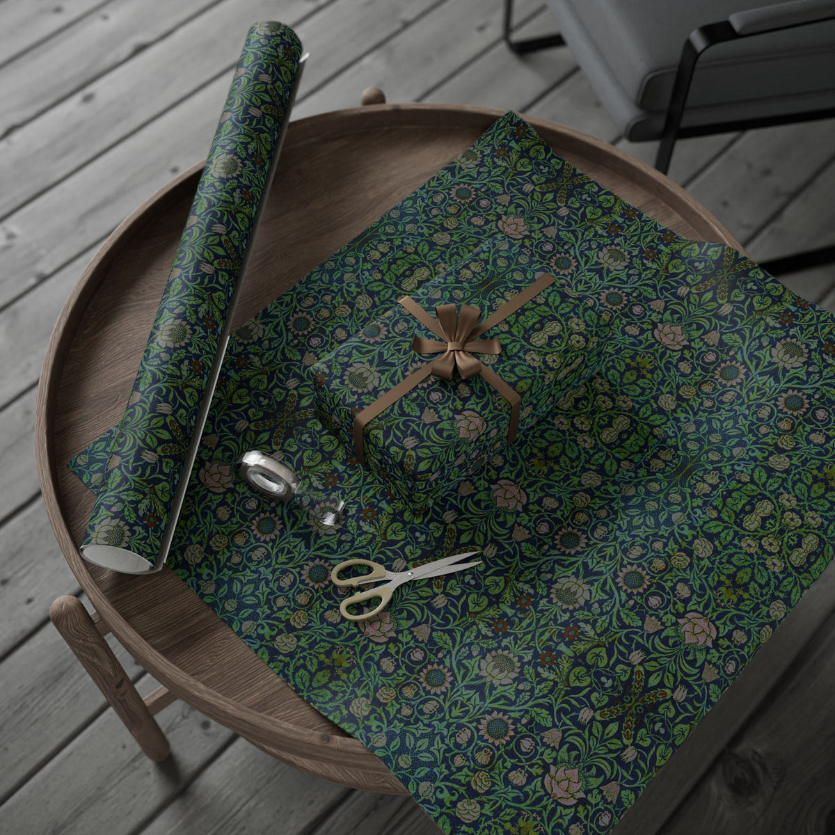Wooden tray with floral-patterned fabric, scissors, and a roll of green paper on a wooden surface.