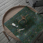 Wooden tray with a green floral-patterned wrapping paper, decorative bow, and scissors on a wooden surface.