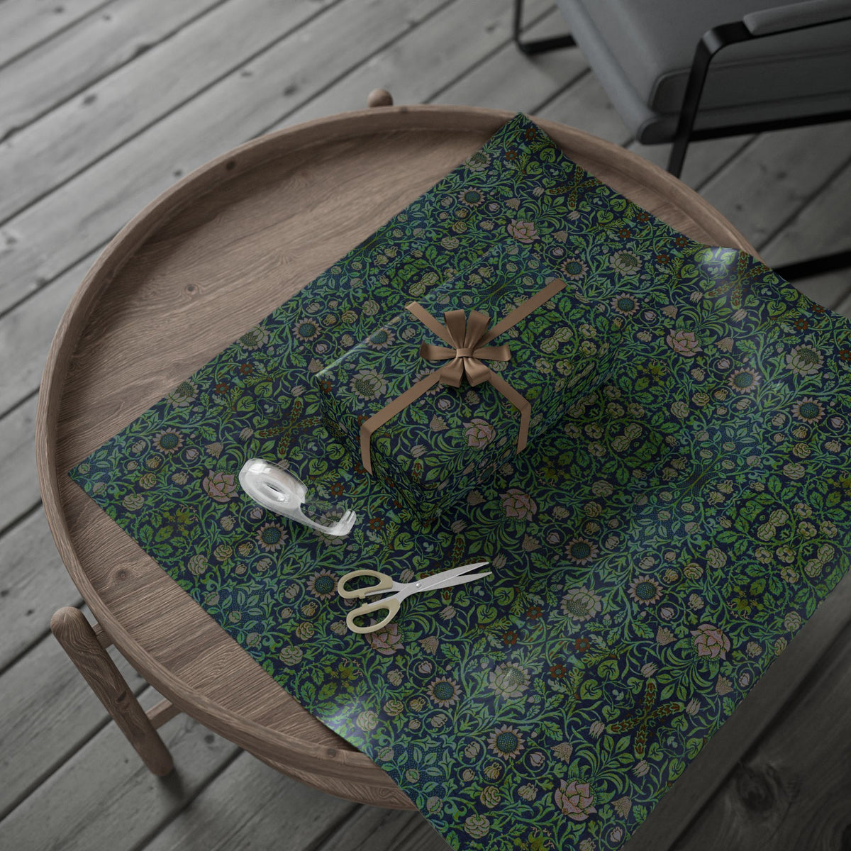 Wooden tray with a green floral-patterned wrapping paper, decorative bow, and scissors on a wooden surface.