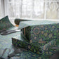 Gift box wrapped in green floral paper with scissors on a table.